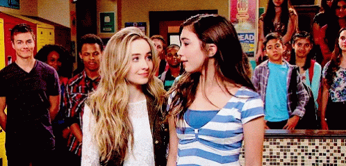 Two Girls Standing Next To Each Other In Front Of A Sign That Says " Head " GIF