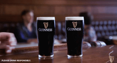 Two Glasses Of Guinness Sit On A Bar In A Restaurant GIF