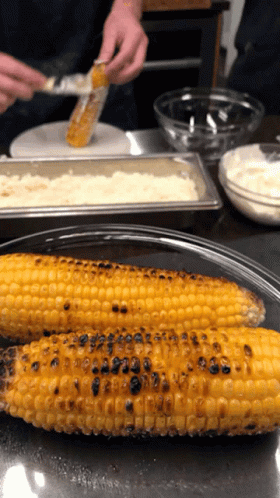Two Grilled Corn On The Cob Are On A Plate GIF