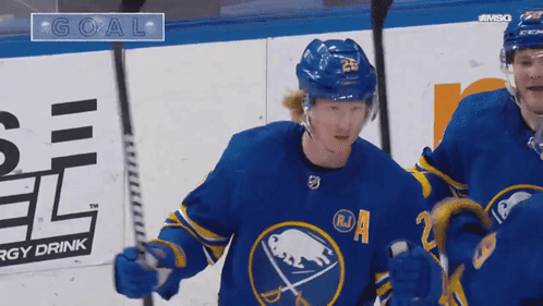 Two Hockey Players Are Celebrating A Goal In Front Of An Energy Drink Advertisement GIF