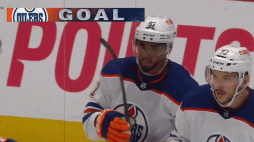 Two Hockey Players Are Standing In Front Of A Banner That Says Oilers Goal GIF