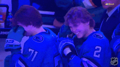 Two Hockey Players Wearing Blue Jerseys With The Number 71 And 2 On Them GIF