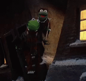 two kermit the frogs are walking down a dark street