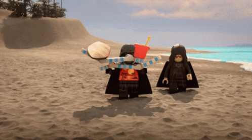 Two Lego Figures Standing On A Sandy Beach With One Holding A Hamburger And The Other Holding A French Fries Bucket GIF