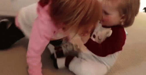 Two Little Girls Are Playing On The Floor With A Teddy Bear . GIF