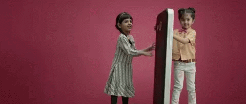 Two Little Girls Holding Large Object GIF