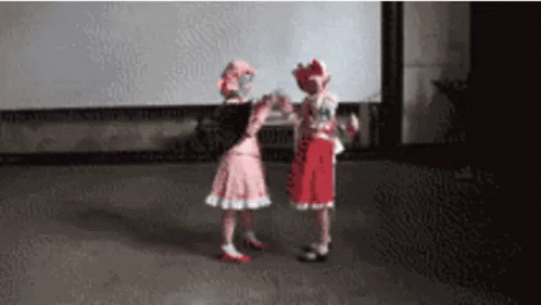 Two Little Girls In Pink And Red Dresses Are Dancing Together On A Stage . GIF