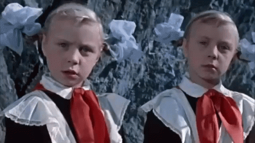 Two Little Girls In School Uniforms Are Standing Next To Each Other . GIF
