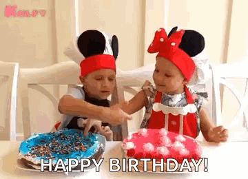 Two Little Girls Wearing Mickey Mouse Hats Are Sitting At A Table With Birthday Cakes . GIF