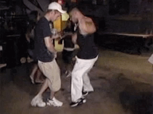 Two Men Are Dancing In A Dark Room While A Man Holds A Guitar . GIF