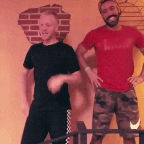 Two Men Are Dancing In A Room With A Brick Wall In The Background . GIF