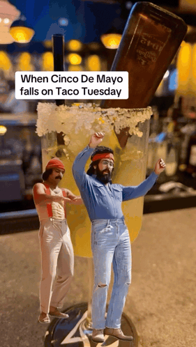Two Men Are Dancing In Front Of A Giant Margarita Glass With A Bottle Of Tequila In The Background GIF