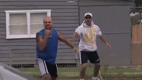 Two Men Are Dancing In Front Of A Gray House . GIF