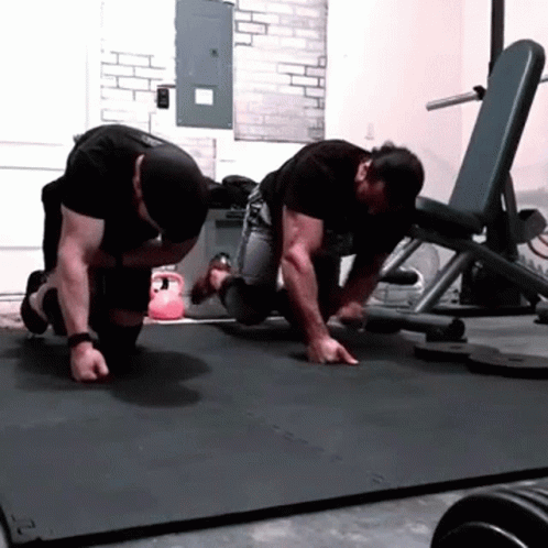 Two Men Are Doing Push Ups On A Mat With The Letter S On It GIF