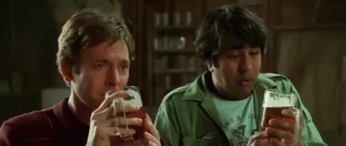 two men are drinking beer together in a bar and talking to each other .