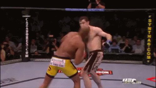 Two Men Are Fighting In A Boxing Ring . One Of The Men Is Wearing Yellow Shorts . GIF