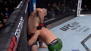 Two Men Are Fighting In A Cage With A Sign That Says Ufc On It GIF