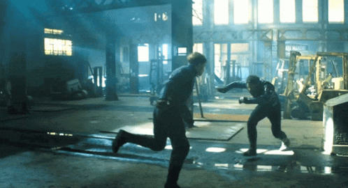 Two Men Are Fighting In A Dark Room With A Sign That Says ' Automotive ' On It GIF