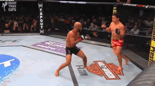 Two Men Are Fighting In A Ring With A Harley Davidson Logo On The Ground GIF
