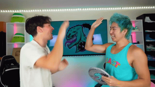 Two Men Are Giving Each Other A High Five In Front Of A Screen With A Monster On It GIF