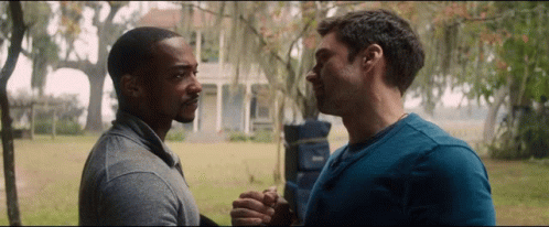Two Men Are Holding Hands In Front Of A House GIF