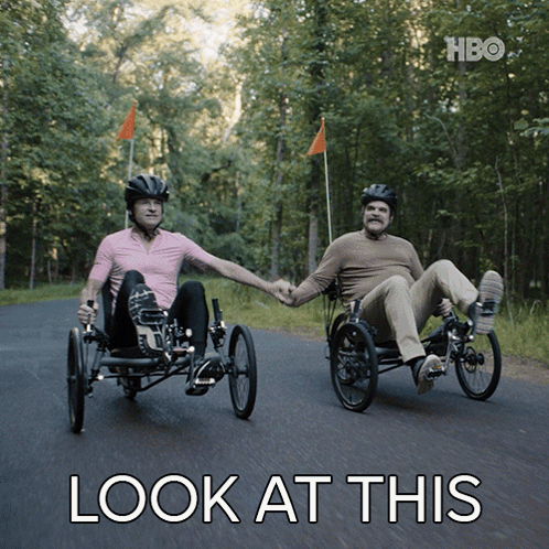 Two Men Are Holding Hands While Riding Three Wheeled Bicycles With The Words Look At This Below Them GIF