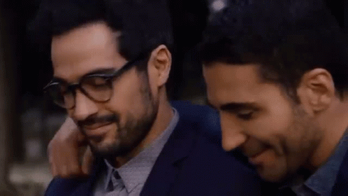 Two Men Are Hugging Each Other And One Of Them Is Wearing Glasses And A Bracelet . GIF