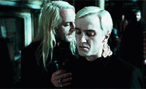 Two Men Are Hugging Each Other In A Dark Room . One Of The Men Is Holding A Glass Of Wine . GIF