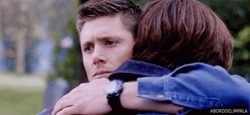 Two Men Are Hugging Each Other In A Park And One Of Them Is Wearing A Watch . GIF
