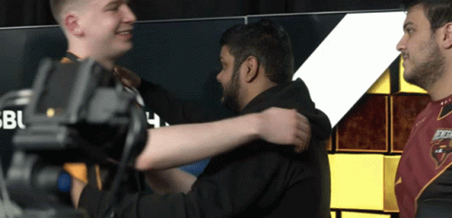 Two Men Are Hugging Each Other In Front Of A Sign That Says Bbc GIF