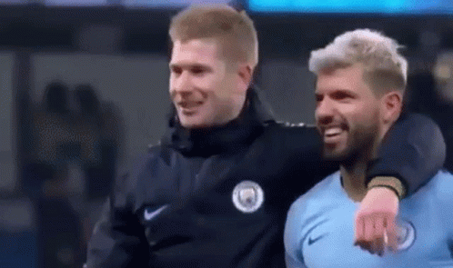 Two Men Are Hugging Each Other On A Soccer Field . GIF