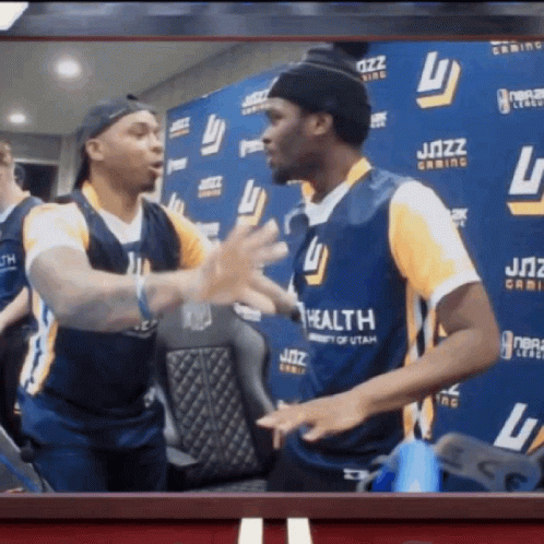 Two Men Are Hugging In Front Of A Wall That Has The Word Jazz On It GIF