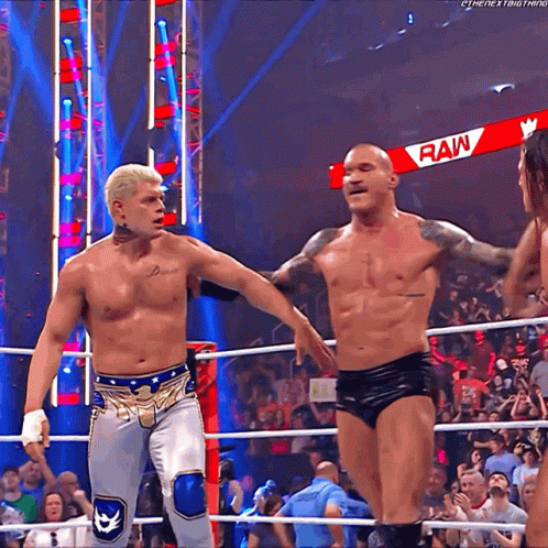 Two Men Are In A Wrestling Ring With A Sign That Says Raw GIF