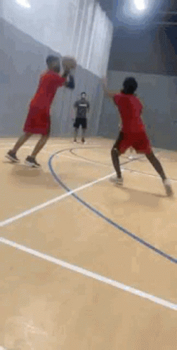 Two Men Are Jumping In The Air On A Basketball Court While Holding Hands . GIF