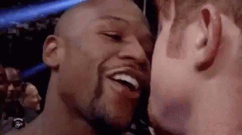 two men are kissing each other on the cheek and smiling .