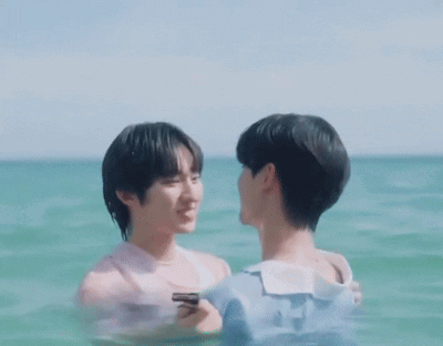 Two Men Are Kissing In The Ocean While One Is Holding A Cell Phone GIF