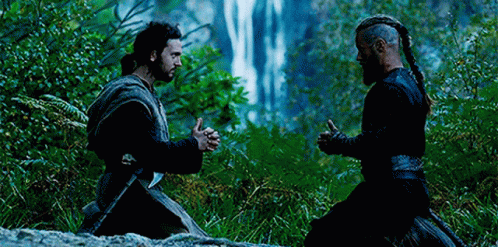 Two Men Are Kneeling In Front Of A Waterfall . GIF