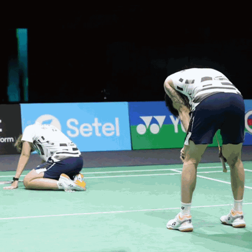Two Men Are Kneeling On A Tennis Court In Front Of A Setel Ad GIF