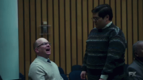 Two Men Are Laughing In Front Of A Wall With Fx On It GIF