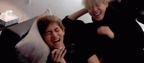 Two Men Are Laying On A Couch And Laughing While One Of Them Is Holding A Cell Phone . GIF