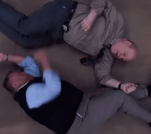 Two Men Are Laying On The Floor Fighting . GIF