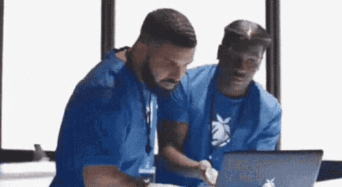 two men are looking at a laptop computer .
