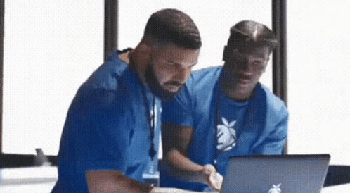 Two Men Are Looking At A Laptop Together . GIF