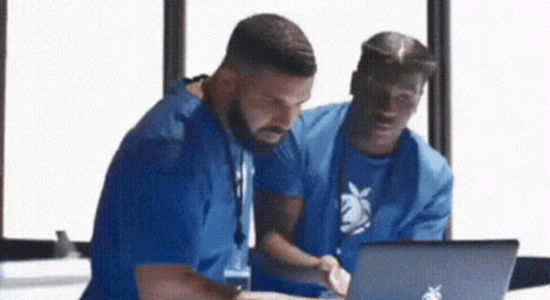 Two Men Are Looking At A Laptop Together . GIF