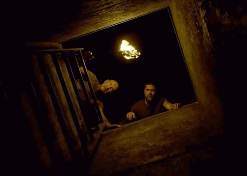 Two Men Are Looking Out A Window At A Torch . GIF