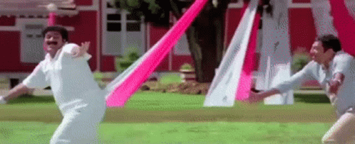 Two Men Are Playing A Game Of Cricket With A Pink And White Flag . GIF