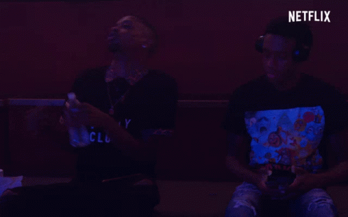 Two Men Are Playing A Video Game With A Netflix Logo Behind Them GIF