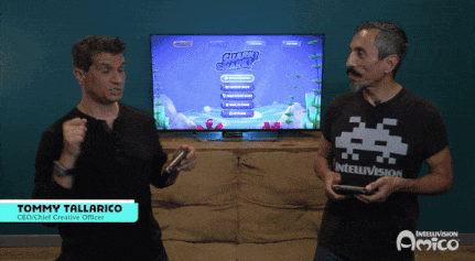 Two Men Are Playing A Video Game With Jimmy Tallarico Standing Behind Them GIF