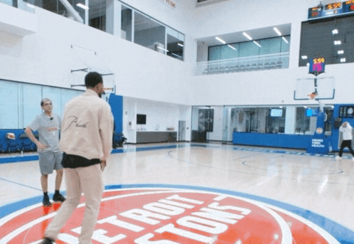 two men are playing basketball on a court with a detroit pistons logo on the floor