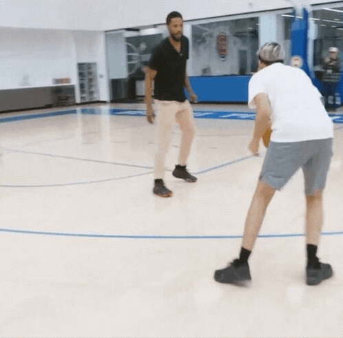 two men are playing basketball on a court with a scoreboard that says 5 to 5